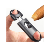Hand holding a black cigar cutter with a can on a white background. Vape Dokha