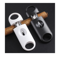 Two cigar cutters, one white and one black, on a black background with cigars.Vape dokha 